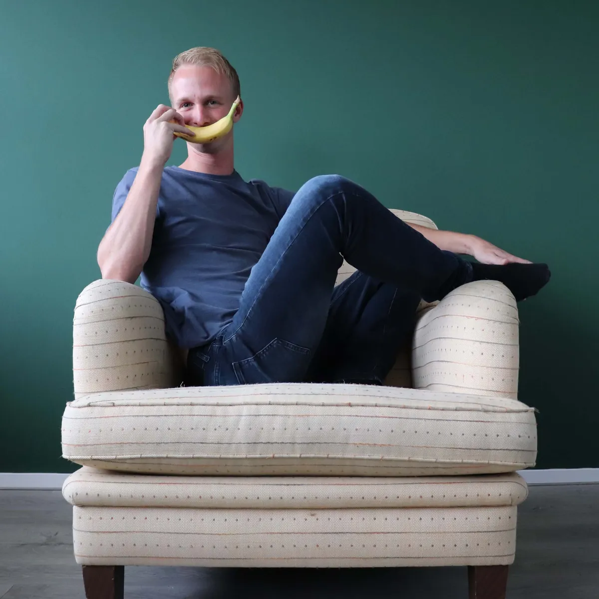 Micky van Zadelhoff in een fauteuil, met een banaan als telefoon