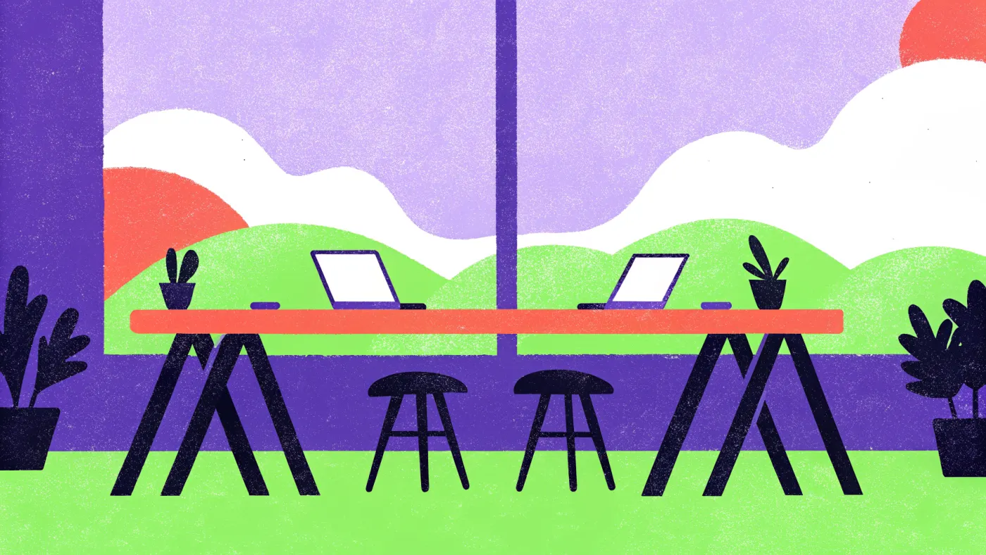 Een goede coworking space: licht, stil en snelle wifi Een lange gedeelde werktafel bij een groot raam met laptops en planten, lege stoelen