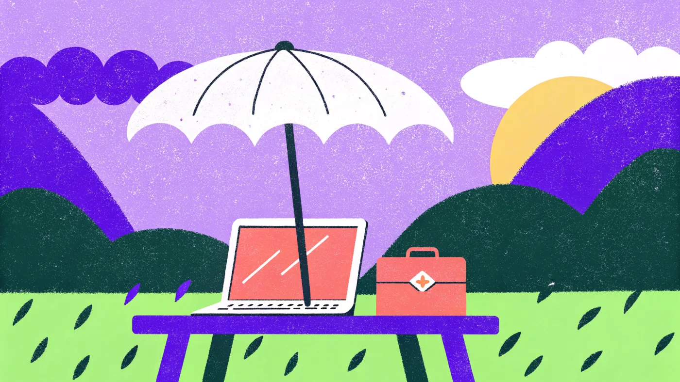 Een kleine paraplu boven een laptop en een EHBO-doos op een houten tafel